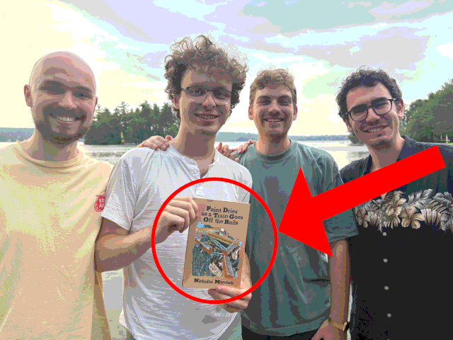 Nick holding a copy of his book, and 3 men standing with him.